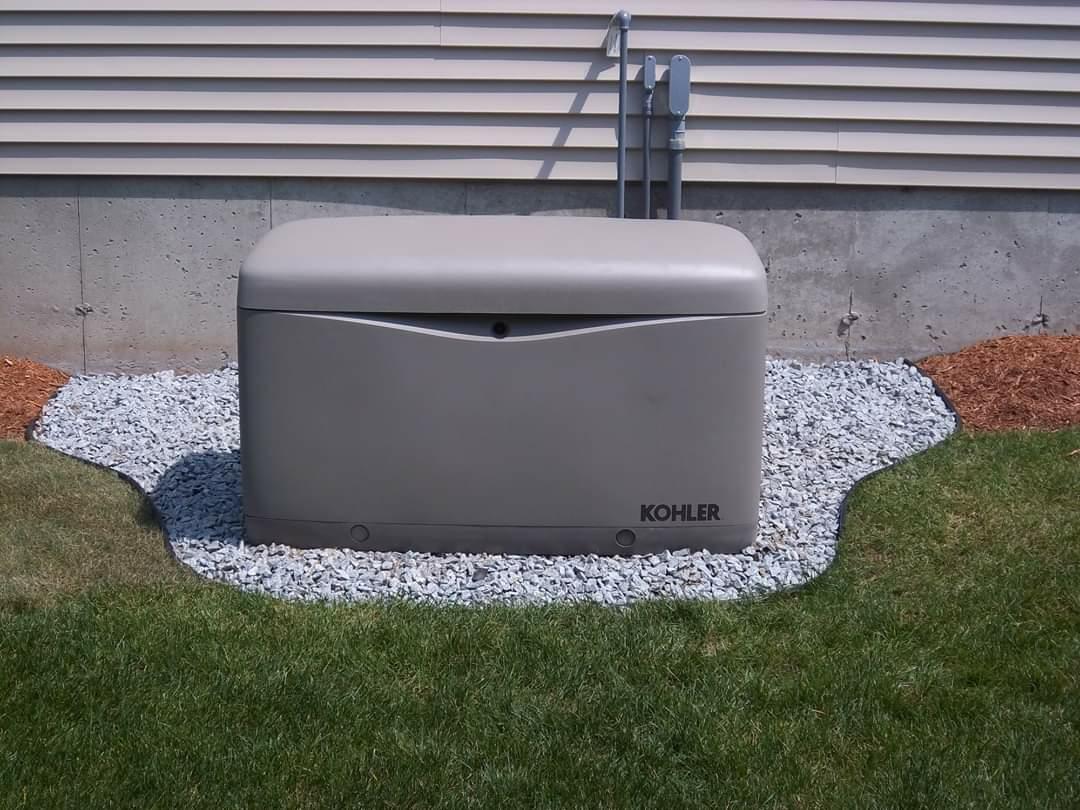 Kohler standby generator installed on a gravel pad beside a house